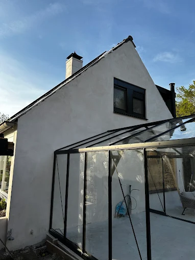 Zwarte serre-uitbouw aan de buitenzijde van een woning